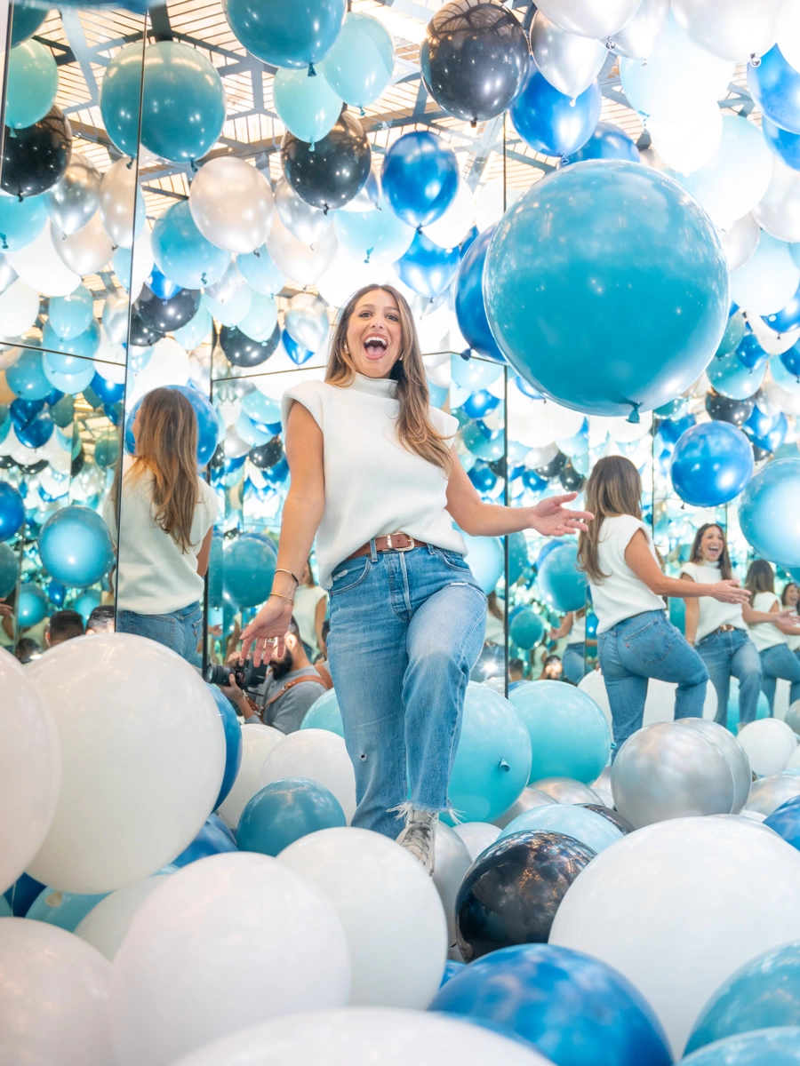 A woman is having fun in a room filled with balloons, her infinite reflections seen in the mirrors, at Museum of Illusions Copenhagen.