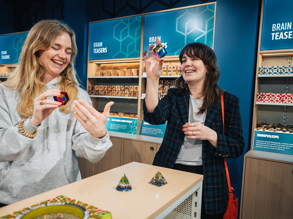 Two young women are checking out brain games and puzzles at the museum shop of Museum of Illusions Copenhagen.
