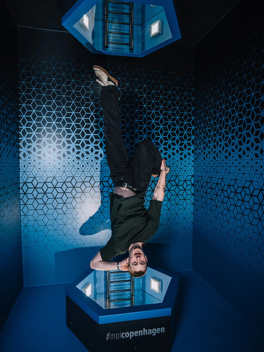 A young man seems to be flying head-down into an Infinity Portal at Museum of Illusions Copenhagen.