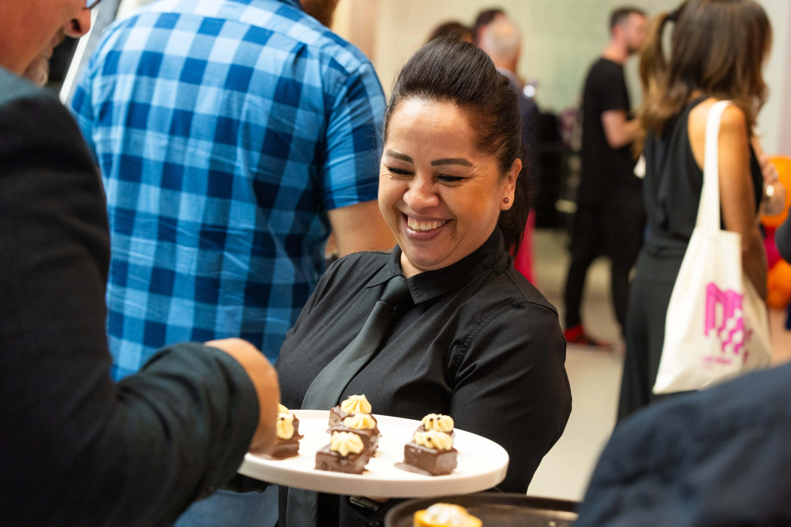 A smiling caterer is serving finger food at an event at Museum of Illusions.