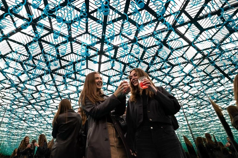 Two young women are holding cocktails at an event at Museum of Illusions Copenhagen.